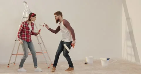 Young cheerful married couple dancing in new apartment with tools for repairs in Stock Footage 144628014