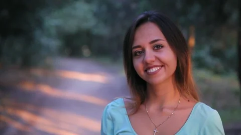 Young cheerful woman smiling at camera in the park at sunset 2 Видео 93863653