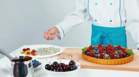 Young chef baker decorating chocolate cake using sweet powder sweets and fruit Video stock 67256065