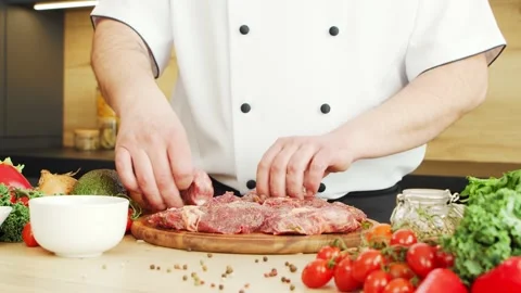 Young chef is cutting meat in a modern kitchen. The man prepares food at home Stock Footage 153782530