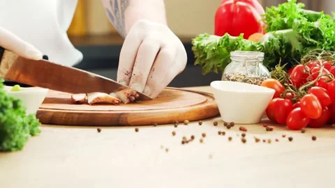 Young chef is cutting octopus in a modern kitchen. The man prepares food at home Stock Footage 153323489