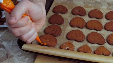 A young chef decorates the gingerbread cookies with orange glaze. Baking Stock Footage 149797658