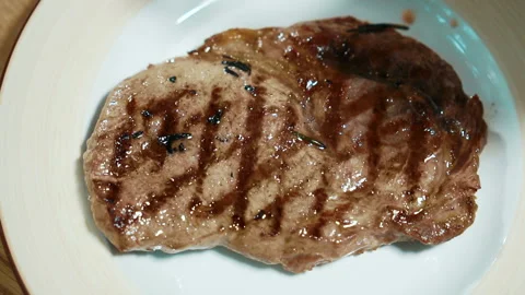 Young chef is decorating roast meat with rosemary in kitchen in restaurant. Stock Footage 86737796