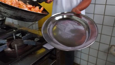 Young chef dumps a pan of cooked shellfish on to a plate in a restaurant kitchen Stock Footage 89790704