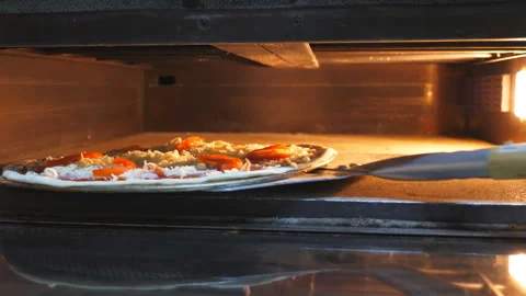 Young chef opening the oven and putting uncooked pizza using a shovel at cuisine Vídeos de archivo 146635751