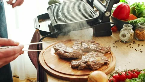 Young chef preparing grilled meat steak in a modern kitchen. The man prepares Stock Footage 153023952