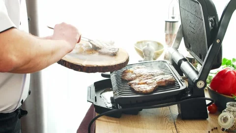 Young chef preparing grilled meat steak in a modern kitchen. The man prepares Stock Footage 153323751
