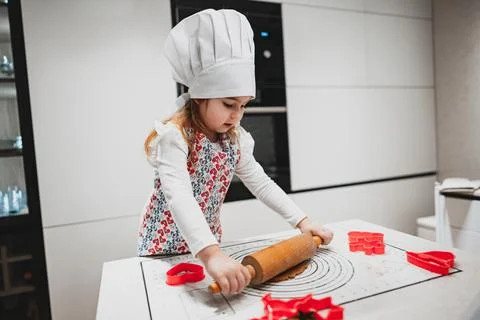 A Young Chef is Rolling Dough in the Kitchen while Joyfully Using Cookie Cutters Stock Photos