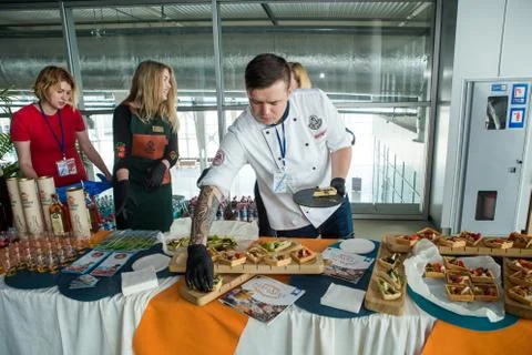 Young chef in white uniform serving snacks on table for degustation in Lviv a Stock Photos