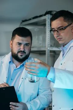 Young chemical technician checking liquid reagent in laboratory Stock-Fotos