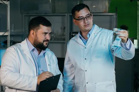 Young chemical technician checking liquid reagent in laboratory Stock Photos