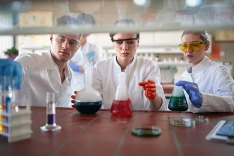 Young chemistry students work with caution while handling dangerous chemicals Stock Photos
