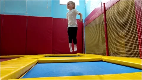 Young child actively jumps high on trampoline, expressing energy and joy during Stock Footage 339864624