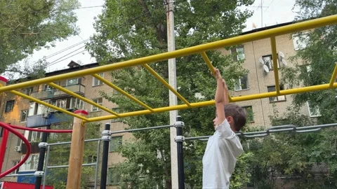 Young child climbing and playing on monkey bars at an outdoor playground. Active Stock Footage 346689473