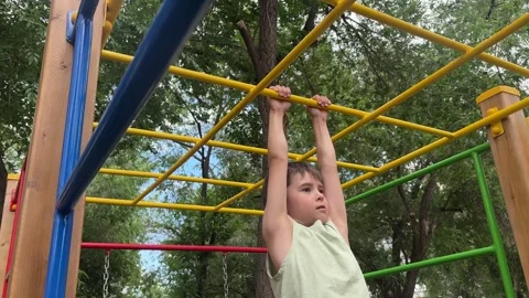 Young child climbing and playing on monkey bars at an outdoor playground. Active Stock Footage 346742786