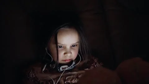 Young child completely absorbed in the captivating glow of a device Stock Footage 303490779
