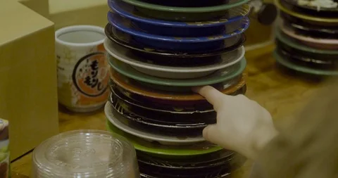 Young child counts stacked plates after a sushi train meal in Japan Stock-Footage 123575283