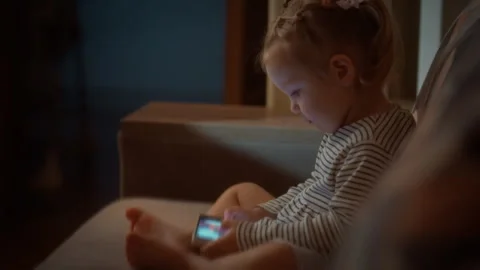 A young child cozied up on the sofa is deeply engaged with vibrant cartoons Stock Footage 331457690