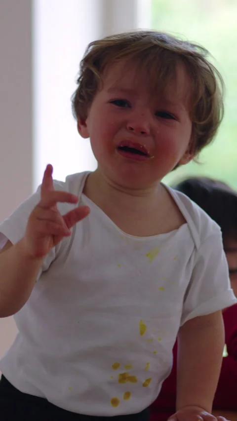 Young child crying at dining table while pointing ahead, emotional sibling .. Stock Footage 336545288