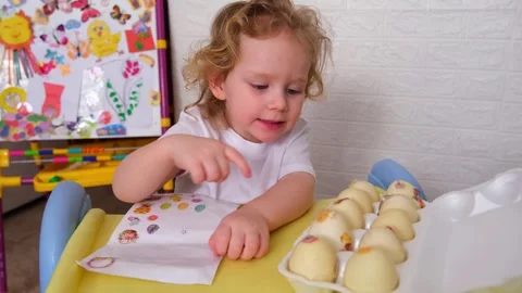Young child decorating Easter eggs with stickers. Happy kid adding colorful Stock-Footage 330108827