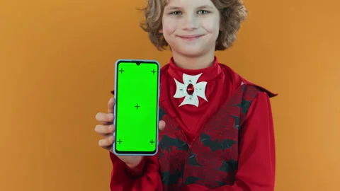 Young Child in Devil Costume Demonstrating Smartphone with Chromakey Screen Stock Footage 285143334