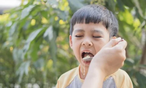 Young child displays disappointment while sitting and crying while eating Stock Photos