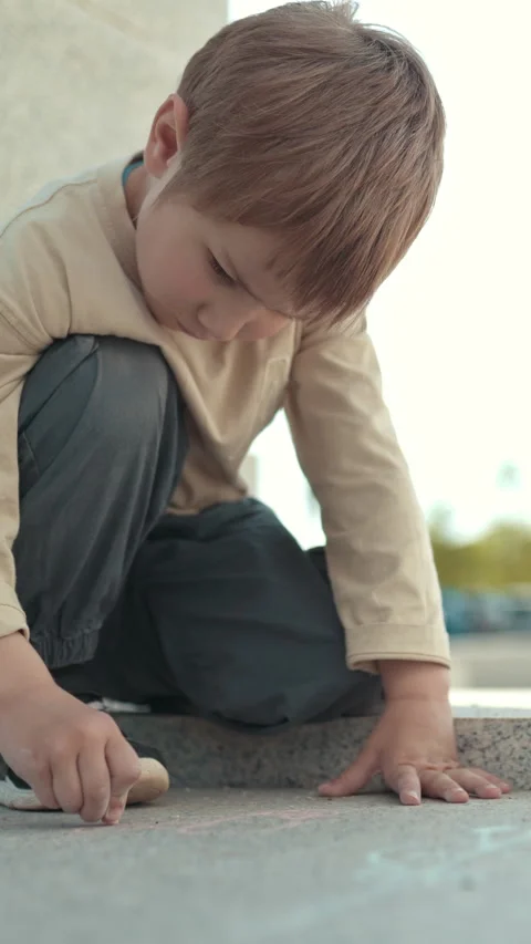 Young child drawing with chalk on pavement Stock Footage 327640804