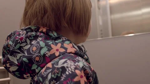 A young child dressed in a colorful jacket is exploring an elevator 스톡 동영상 311117433