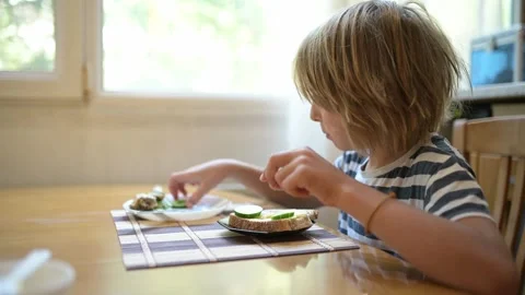 Young child eating plain bread at breakfast table in cozy kitchen. Peaceful Stock Footage 315574259