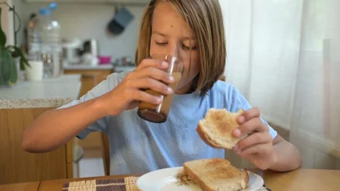 Young child eating plain bread at breakfast table in cozy kitchen. Peaceful Stock Footage 315605540