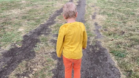 Young Child Embarks on a Solo Walk Down a Wet Path After a Summer Rain Video stock 311561306