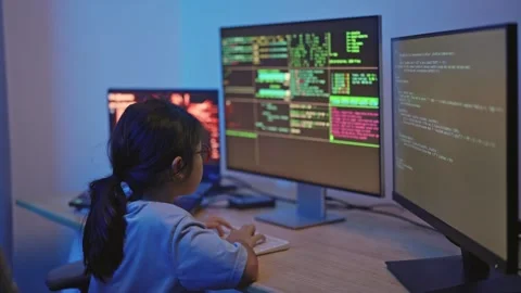 Young Child Engaged in Coding with Computer Screens Displaying Colorful Cod.. Stock Footage 319928943