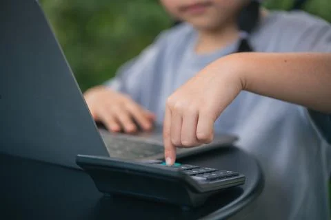 Young Child Engaged in Online Learning Using Laptop and Calculator to Enhan.. Stock Photos