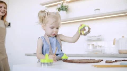 Young child engages in creative baking activity in a bright kitchen while using Stock Footage 308490722
