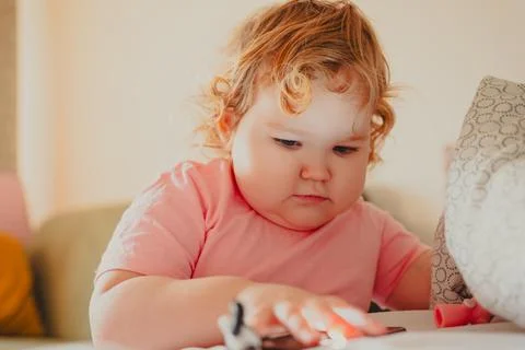 Young Child Engaging With Smartphone While Playing With Small Toys in Cozy In Stock Photos