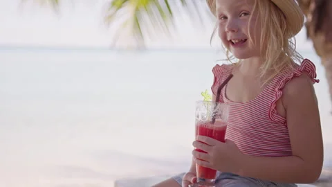 Young child enjoys a refreshing drink in a tropical setting by the beach during Stock Footage 293106523