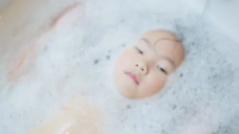 Young child enjoys a relaxing bubble bath at home Stock Footage 339047507
