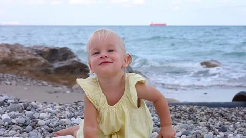 Young child exploring pebbles at the beach during a sunny afternoon by the sea Stock Footage 285084942