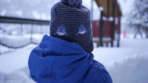 Young child in front of a playground covered with snow Stock Footage 104900406