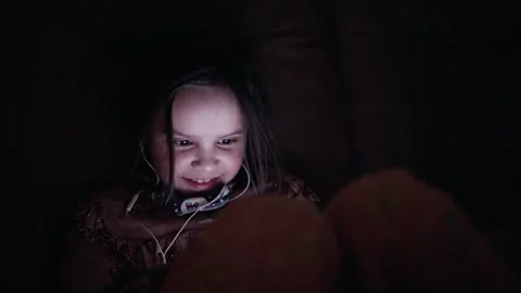 A young child happily smiling while absorbed in watching a screen in the soft Video stock 305459863