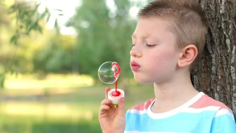 Young child has fun making soap bubbles at the park on a sunny day 動画素材 135381058