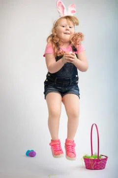 Young child holding a easter egg jumping with pink basket Stock Photos