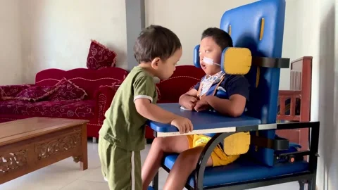 Young child interacting with a peer using a specialized adaptive seating chair Stock Footage 342090440