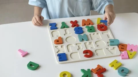 Young child interacts with bright letter puzzle, carefully fitting colorful Stock Footage 318294675