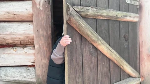 A young child joyfully explores the rustic cabin door, feeling adventure in Stock Footage 304731164