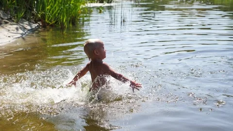 Young child joyfully exploring sandy shore, stepping down towards water Video stock 317372335