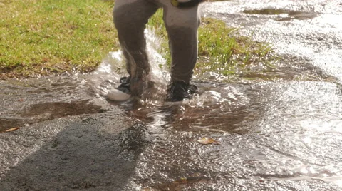 Young child jumping happily in puddle Video stock 53876173