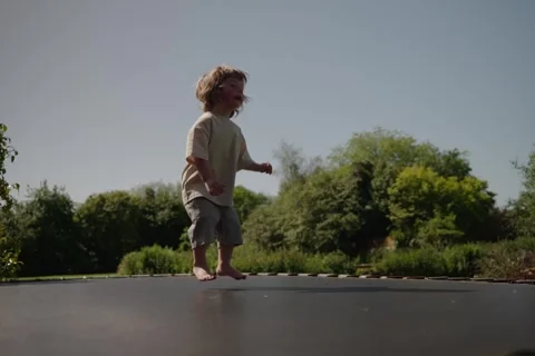 Young Child Jumping on Trampoline Low Angle View Outdoors 4K Stock Footage 335704636