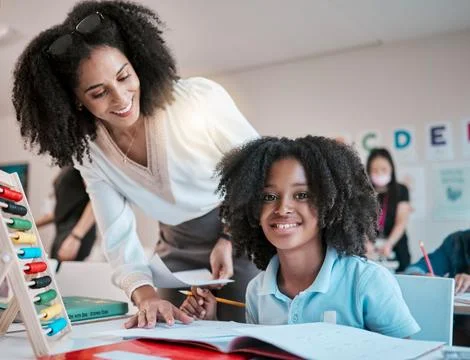 Young child learning maths, happy teacher in classroom with children and Stock Photos