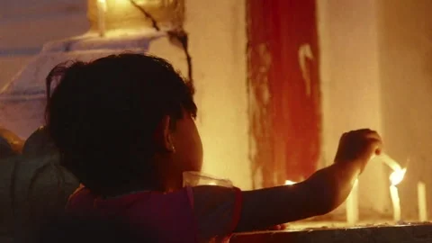 Young child lighting a candle in a temple 스톡 동영상 332766972